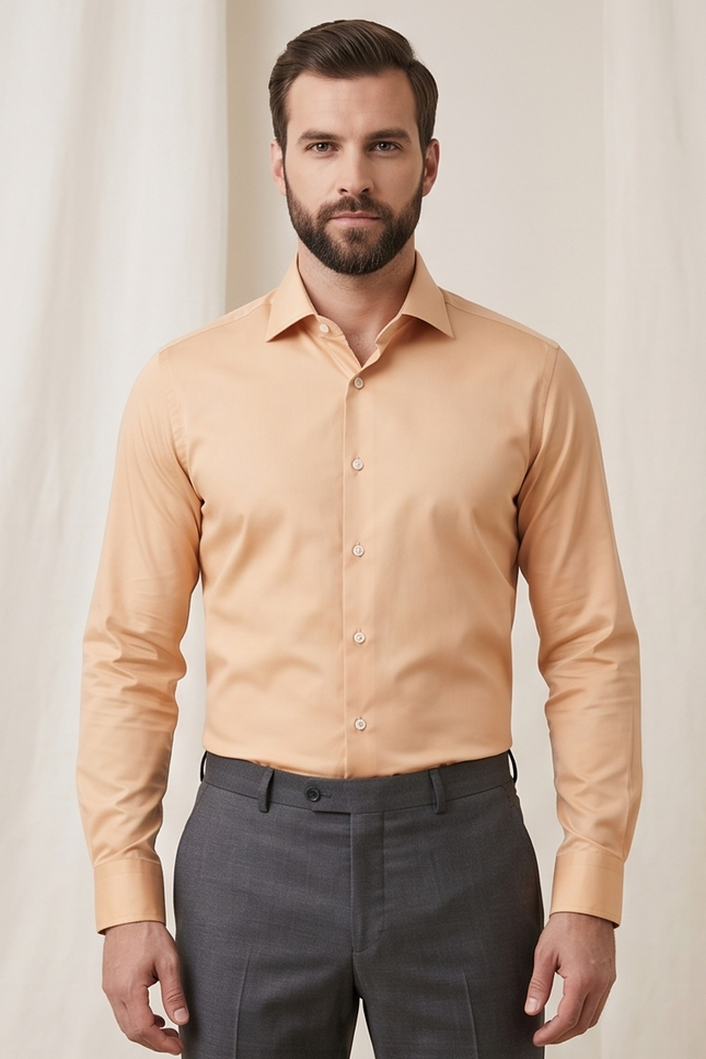Man wearing a peach-colored dress shirt and gray pants against a plain background