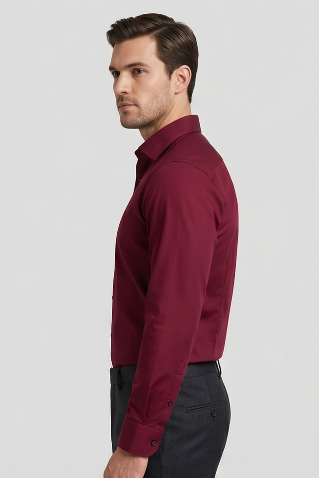 Man wearing a burgundy dress shirt and dark pants on a light gray background