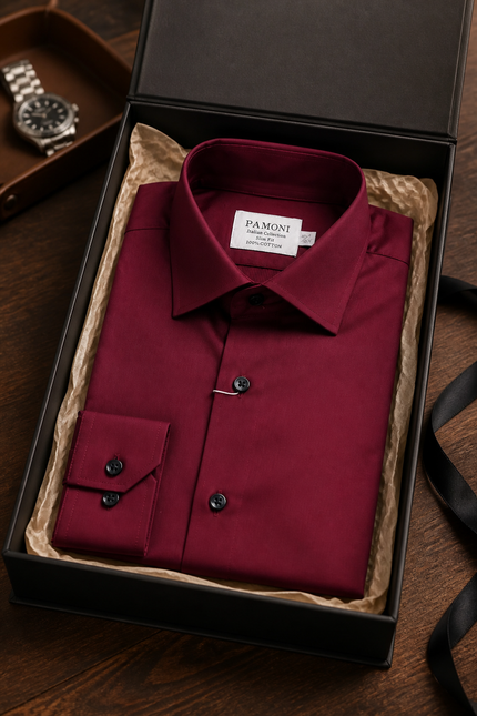 Red dress shirt in a black box with 'Pamoni' label, watch partially visible on wooden surface.