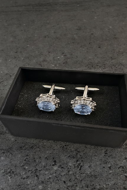 Pair of cufflinks with blue gemstones in a black box on a dark surface
