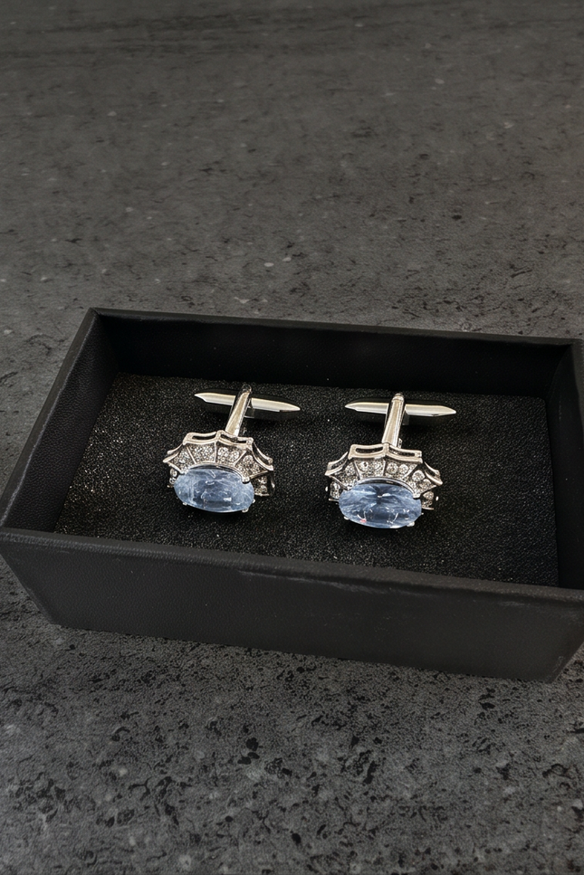 Pair of cufflinks with blue gemstones in a black box on a dark surface