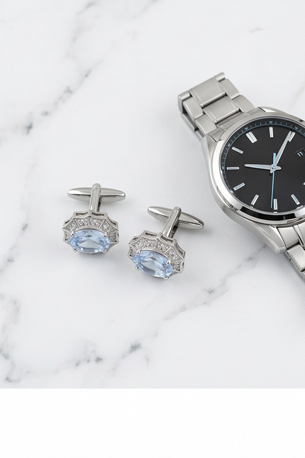 Silver watch and cufflinks with gemstones on a marble surface