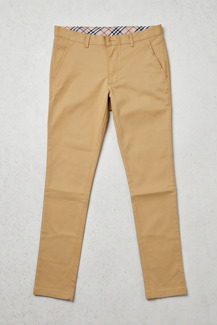 Beige pants with a brand label on a light gray background