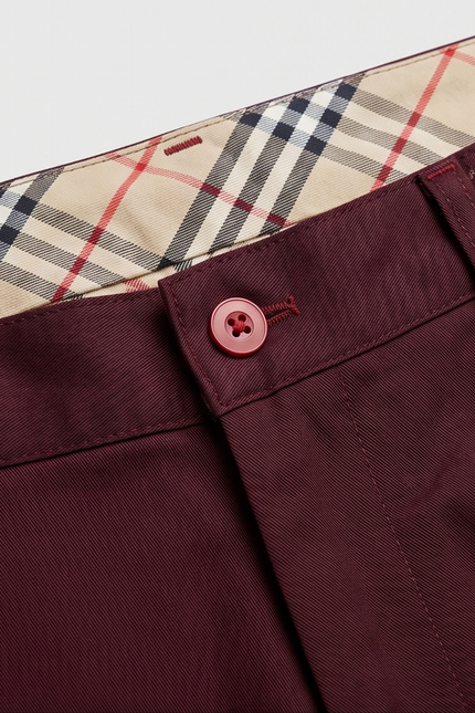 Close-up of maroon pants with a plaid lining on a white background