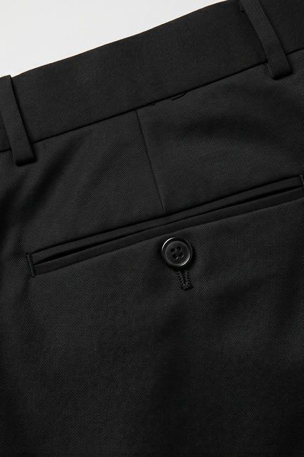 Close-up of black pants with a button on a light gray background