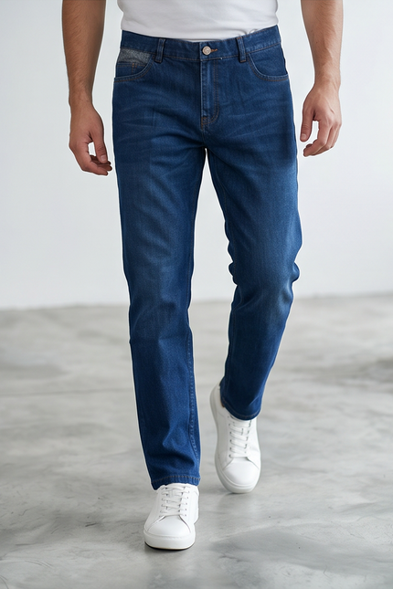 Person wearing blue jeans and white sneakers on a plain background
