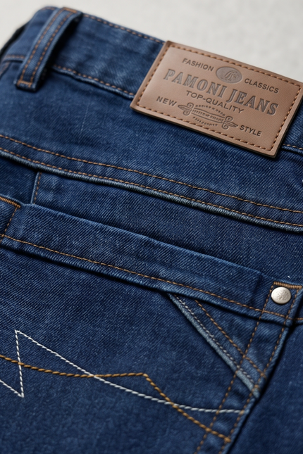 Close-up of blue jeans with a Pamoni Jeans label on a light gray background
