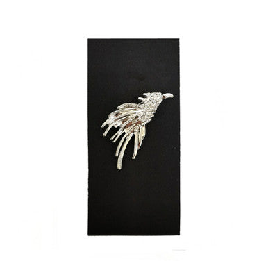 Silver jewelled phoenix lapel pin by PAMONI featuring intricate design with sparkling gemstones on a polished metal background.